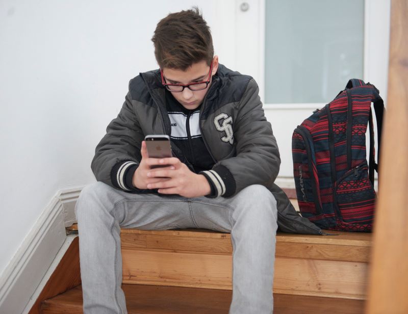 Junge starrt auf sein Handy und ruft Nummer gegen Kummer an