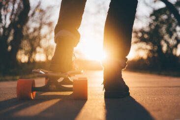 Kind auf einem Skateboard vor Sonnenuntergang